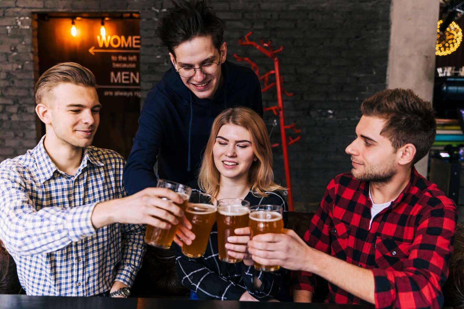 amigos-felices-tintineando-vasos-cerveza-restaurante